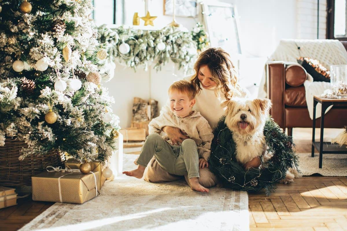 madre, hijo y un perro junto a un árbol de Navidad