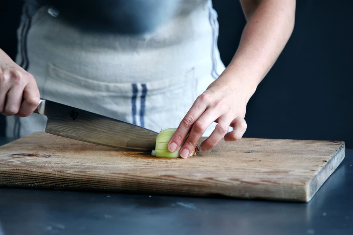 mujer cortando un pepino en una tabla de madera