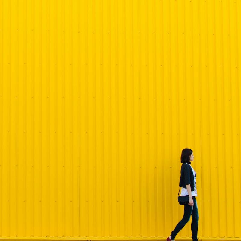 mujer delante de pared alta amarilla