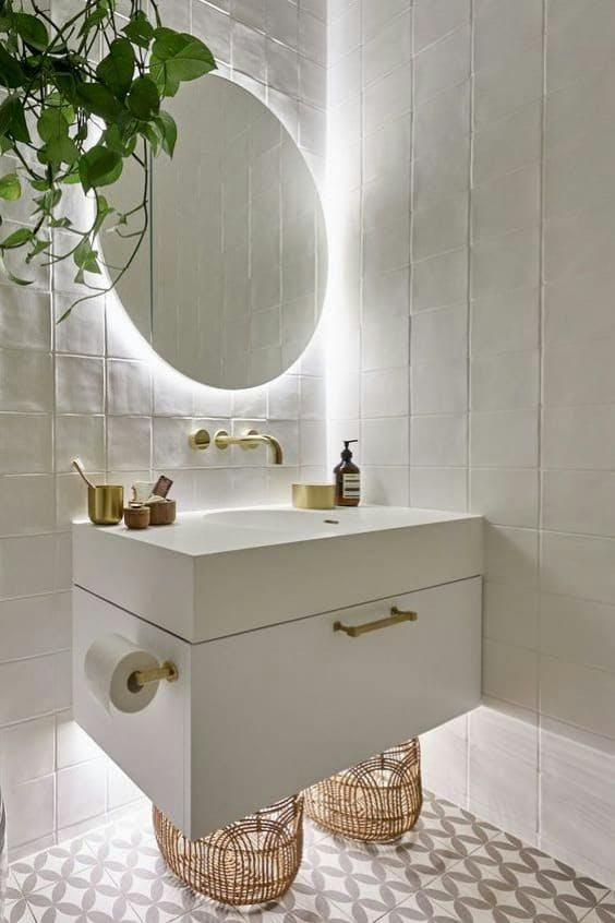 Baño en blanco con espejo redondo y mueble suspendido iluminado