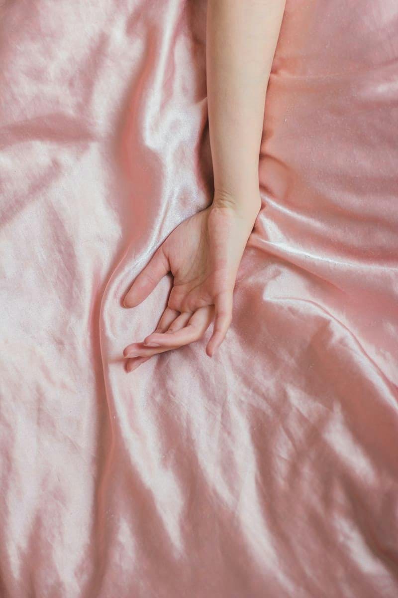 mano sobre sábana de seda rosa