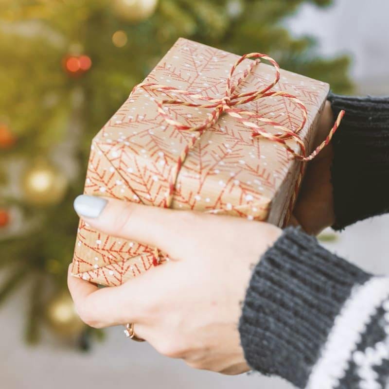 manos de mujer entregando un regalo de Navidad